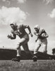 Two football players running with a football on a football field Poster Print - Item # VARSAL2555424B