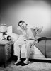 Mid adult man wearing pajamas sitting on bed Poster Print - Item # VARSAL255420149