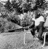 Chimpanzee sitting on a chair and watering a lawn Poster Print - Item # VARSAL9901554