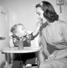 Baby boy sitting in high chair feeding mother with cookie Poster Print - Item # VARSAL2556008