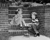 Boy putting a roller skate on his sister's foot Poster Print - Item # VARSAL25516327