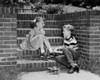 Boy putting a roller skate on his sister's foot Poster Print - Item # VARSAL25516327