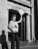 Boy selling newspapers in front of a building Poster Print - Item # VARSAL25539099