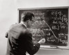 Rear view of a male teacher writing with chalk on a blackboard Poster Print - Item # VARSAL2553758