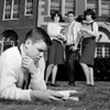 Students watching friend reading on grass outside university Poster Print - Item # VARSAL255418380