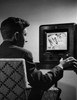 Young man changing channels of a television Poster Print - Item # VARSAL2551658