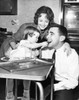 Girl feeding a cookie to her father with her mother looking at them Poster Print - Item # VARSAL25542741