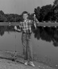 Boy standing in front of pond holding fishing rod and fish Poster Print - Item # VARSAL255418569