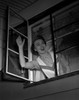 Woman looking through window and waving Poster Print