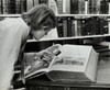 Young man examining a miniature Bible in a library Poster Print - Item # VARSAL990118200