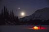 Nighttime view of a man standing next to a lit tent on a snow covered Trail Lake with the moon, stars, and planets overhead, Moose Pass, Kenai Peninsula, Southcentral Alaska Poster Print by Kevin G. Smith / Design Pics - Item # VARDPI12272196