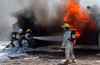 Airman looks on as fellow firefighters rush in to battle a blaze Poster Print by Stocktrek Images - Item # VARPSTSTK101074M