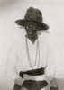 African American woman, half-length portrait, wearing large hat and bead necklace, standing, facing front with hands together at waist. Poster Print - Item # VARBLL058763474x