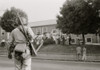 Armed member of the National Guard observing Clinton High School as students stand on its steps and lawn. Poster Print - Item # VARBLL0587633379