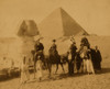 Three women and a man in western attire, seated on camels, several local men stand before the camels holding the reins, a pyramid and the sphinx in background Poster Print - Item # VARBLL058754083L