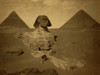 Three men, one with camel, on paw of the Sphinx, two pyramids in background. Poster Print - Item # VARBLL058754022L