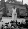 African American woman feeds chicks outside of her cabin while a young girl looks on Poster Print - Item # VARBLL058744987L