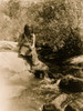 Miwok man holding spear, sitting on boulder in a creek. Poster Print - Item # VARBLL058746916L