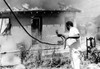 A Man Attempts To Stop The Fire Destroying His Home During The Watts Riots. Firemen Were Unable To Enter The Area History - Item # VAREVCHBDRIOTCS010