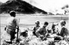 Korean War-A U.S. Medic Gives First Aid To A Wounded Machine Gunner On The South Korean Battle Front. In Background Smoke & Fire Rise Froma A Burning Village.  8-6-50 - Cpl ArchivesEverett Collection History - Item # VAREVCHBDKOWACL001