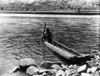 Nez Perc_ Canoe. Nez Perc_ Man With Pole Maneuvering Dugout Canoe To Rocky Shore. Edward S. Curtis History - Item # VAREVCHCDLCGCEC244