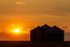 Silhouette of large metal grain bins at sunrise with orange sun rising over clouds; Alberta, Canada Poster Print by Michael Interisano / Design Pics - Item # VARDPI12516718