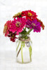 A variety of coloured Zinnia flowers in a simple glass vase with a decorative heart pendant held in place with a jute string Poster Print by Lorna Rande / Design Pics - Item # VARDPI12513685