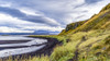 Typical landscape of Iceland with green tundra, black sand along the water's edge and  a mountainous region under a cloudy sky; Iceland Poster Print by Keith Levit (20 x 11) # 13184897