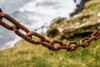Rusted chain hanging with a coastal landscape in the background; Hafnarfjorour, Southern Peninsula Region, Iceland Poster Print by Keith Levit (19 x 12) # 13185339