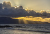 Beautiful sunlight rays stream through the dark clouds and fading daylight over the pacific ocean on a secluded Maui, Hawaii beach The rocks and islands are silhouetted by the sunset light; Maui, Hawaii, United States of America Print