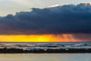 Dramatic sunrise over Lydgate Beach, breakwater and the ocean from the coast of Kauai with dark storm clouds and a distant rainfall; Kapaa, Kauai, Hawaii, United States of America Poster Print by The Nature Collection (19 x 12) # 12575085