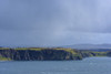 Sunlit sea cliffs and rainclouds along the coast of the Isle of Skye in Scotland, United Kingdom Poster Print by Raimund Linke (19 x 12)
