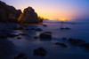 Rock formations along El Matador State Beach at night with the city lights of Los Angeles in the background; Malibu, California, United States of America Poster Print by Ben Horton (19 x 12)