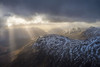 Sun breaking through cloud over snowy mountains near Glenfinnan; Scotland, United Kingdom Poster Print by Ian Cumming (20 x 13)