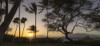 Silhouette of tropical trees along the shore at Keawakapu Beach with golden sun rays over the Pacific Ocean at twilight; Kihei, Wailea, Maui, Hawaii, United States of America Poster Print by Living Moments Media (21 x 9)