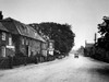Magic lantern slide circa 1900.Victorian/Edwardian.Social History. A suffolk country street with a draper,hosier shop and a vintage car driving on the road Poster Print by John Short (18 x 13)