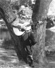 Gene Autry playing guitar against a tree Photo Print - Item # VARCEL681209