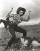 Jane Russell Posed in Checkered Tight Long Sleeve Collar Shirt and High Waist Linen Pants with Cowboy Hat while Hands Raised Up and Feet Apart Photo Print - Item # VARCEL687563