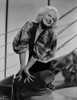Jean Harlow Posed and Knelt on the Couch in Black Deep V-Neck Velvet Dress and Cotton Pleated Broad Sleeves with Hands on the Knees Photo Print - Item # VARCEL696742