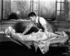 Jean Harlow Scene from a Film sitting on a Straw Covered Bed in White Silk Dress Photo Print - Item # VARCEL697190