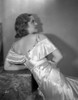 Bette Davis Leaning Back on the Table Facing Back and Looking Up in White Silk Dress Photo Print - Item # VARCEL692874