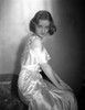Bette Davis Seated on a Couch with Hands on the Knee in White Strap Dress Photo Print - Item # VARCEL692979