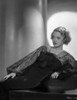 Bette Davis Reclining on the Table with Hand on the Skirt in Black Sheer Lace Long Sleeve Dress Photo Print - Item # VARCEL693286