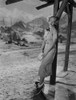 Bette Davis Posed Holding a Book while Leaning Back on a Wood Post in White Striped Dress and Black Ribbon Tie Photo Print - Item # VARCEL693361