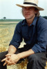 Alexander Godunov sitting on a Hay Stack wearing Blue Long Sleeves and a Hat Photo Print - Item # VARCEL694868