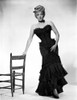 Marlene Dietrich standing in Strapless Black Dress with Chair Photo Print - Item # VARCEL695222
