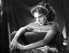 Jean Simmons Posed and sitting on the Couch in White Pleated Dress and Silk Scarf with Hands Together Photo Print - Item # VARCEL704695
