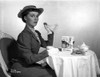 Phyllis Kirk Seated while Holding Cookie in Black Formal Dress with Hat Photo Print - Item # VARCEL706145
