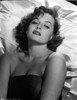 Victoria Shaw laying on all white, smooth silk linens, wearing a black sleeveless top, looking up into the camera Photo Print - Item # VARCEL707980