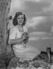 Shirley Temple Kneeling on the Ground and Leaning on a Tree Photo Print - Item # VARCEL708475